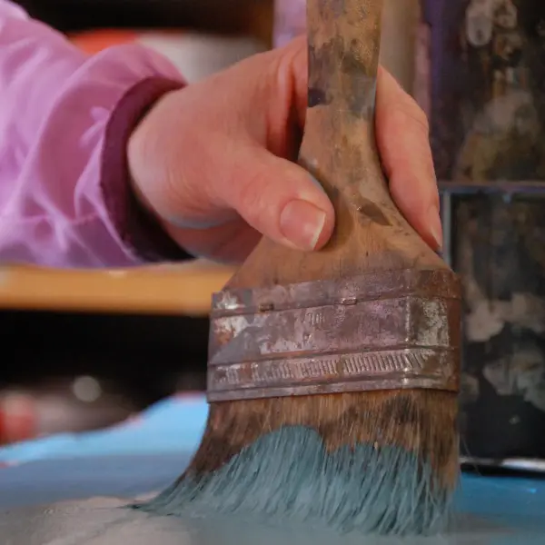 A person holding a paintbrush in their hand.