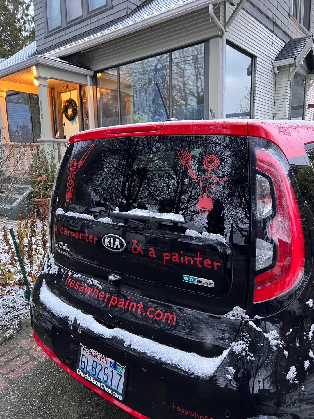 A red car with black lettering and snow on the back.